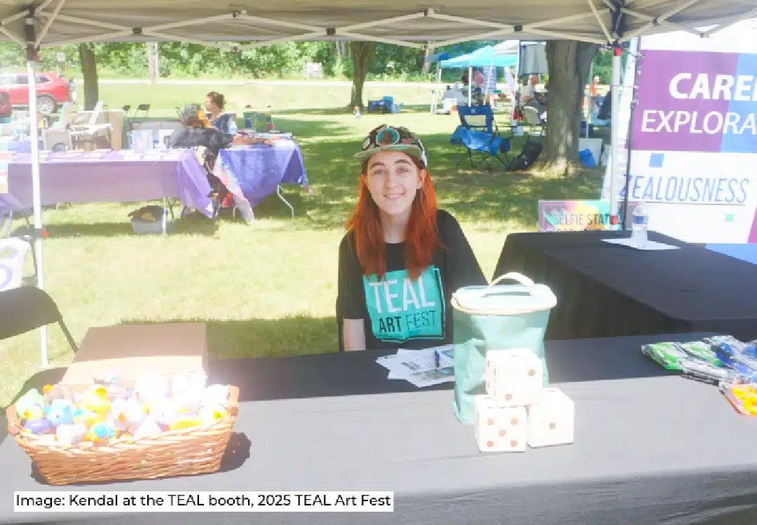 image of a young female wearing TEAL Art Fest t-shirt sitting at the vendor booth